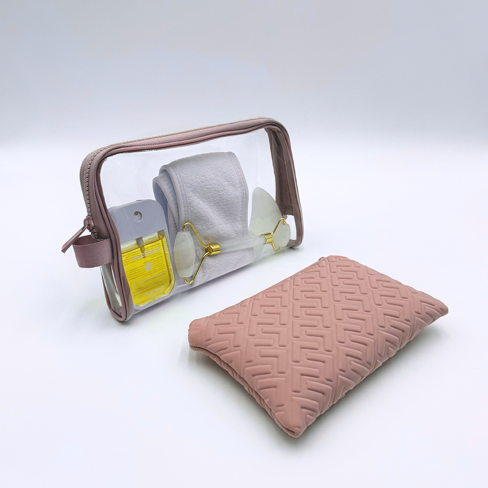 Clear travel bag with sunglasses, hairbrush, and pink pouch on a white background