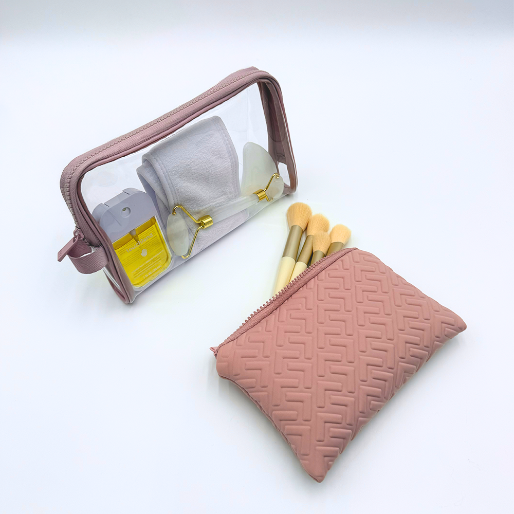 Pink makeup bag with glasses, earrings, and brushes on a white background
