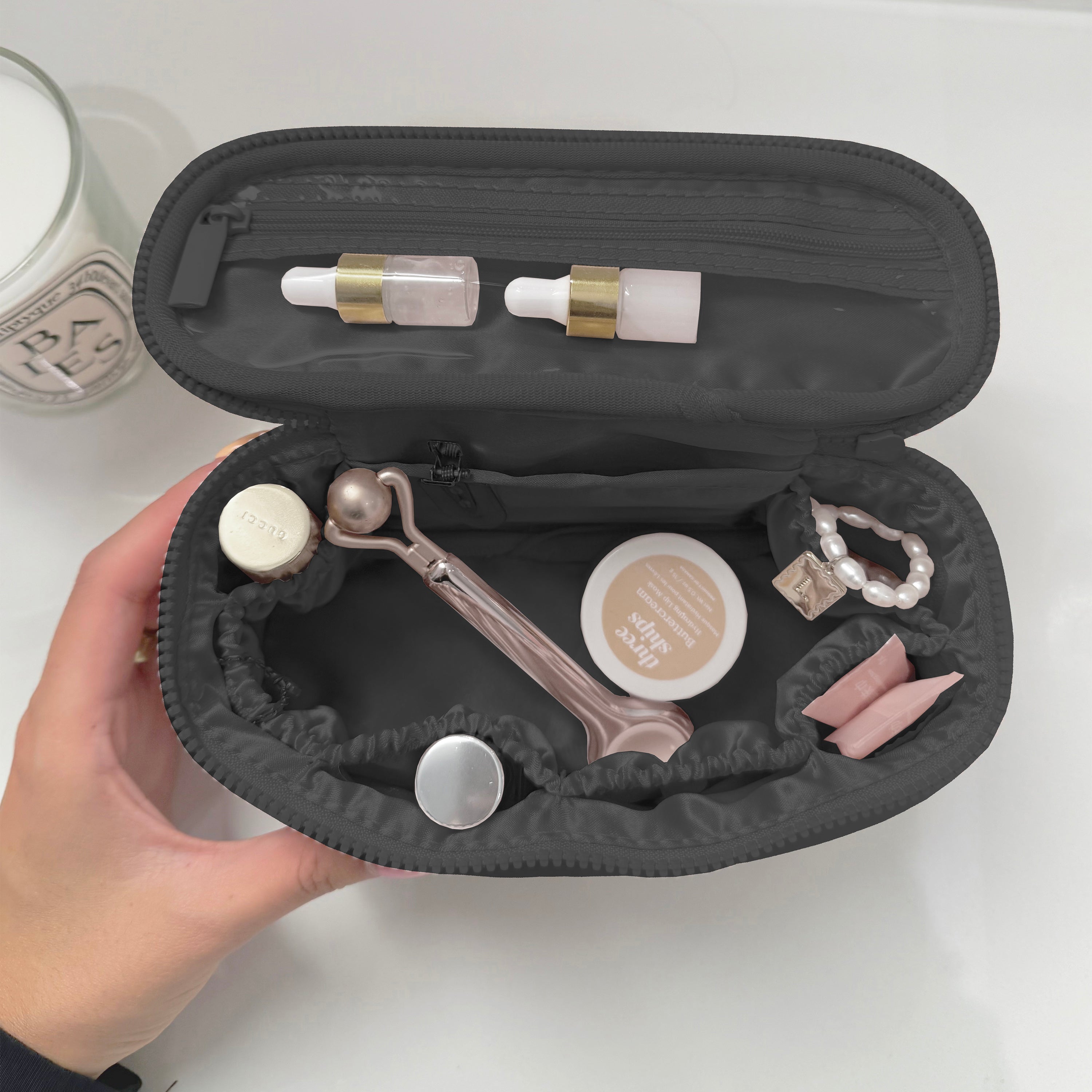 Black travel case with skincare products and accessories on a white background