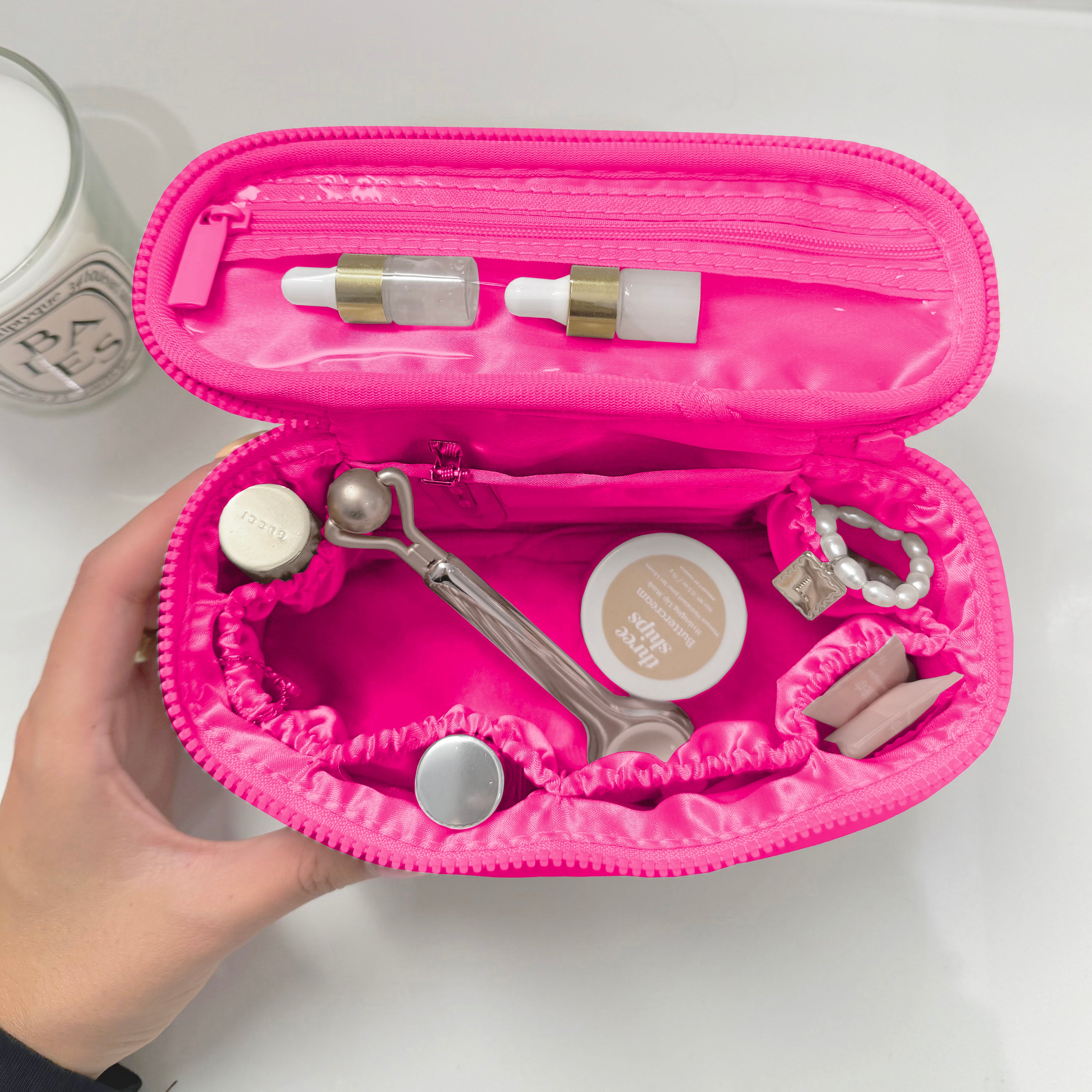 Pink makeup case with various cosmetic items on a white background